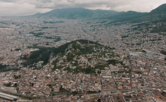 An aerial shot of the cityscape of Quito spread on mountains under the cloudy sky in Ecuador